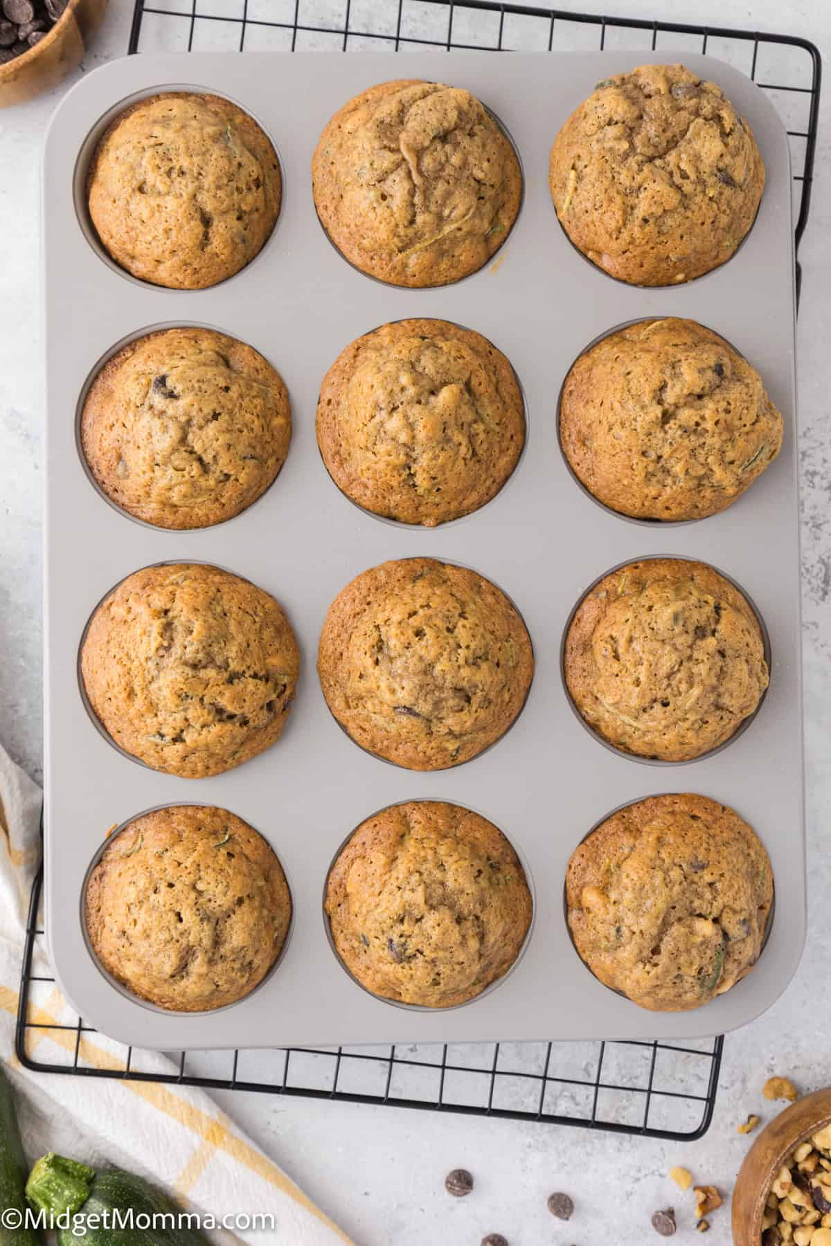 A muffin tin with twelve freshly baked muffins on a cooling rack.