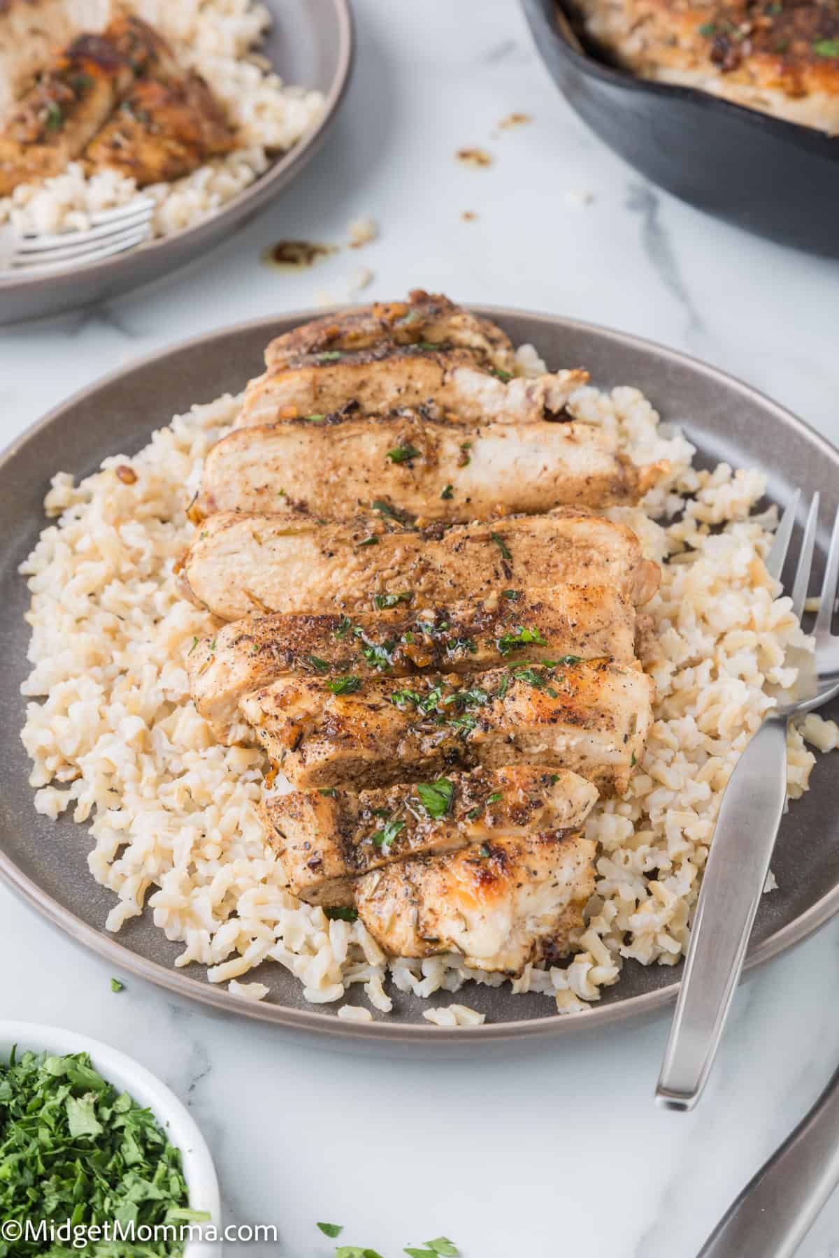Skillet garlic butter chicken served over rice on a grey plate with a fork