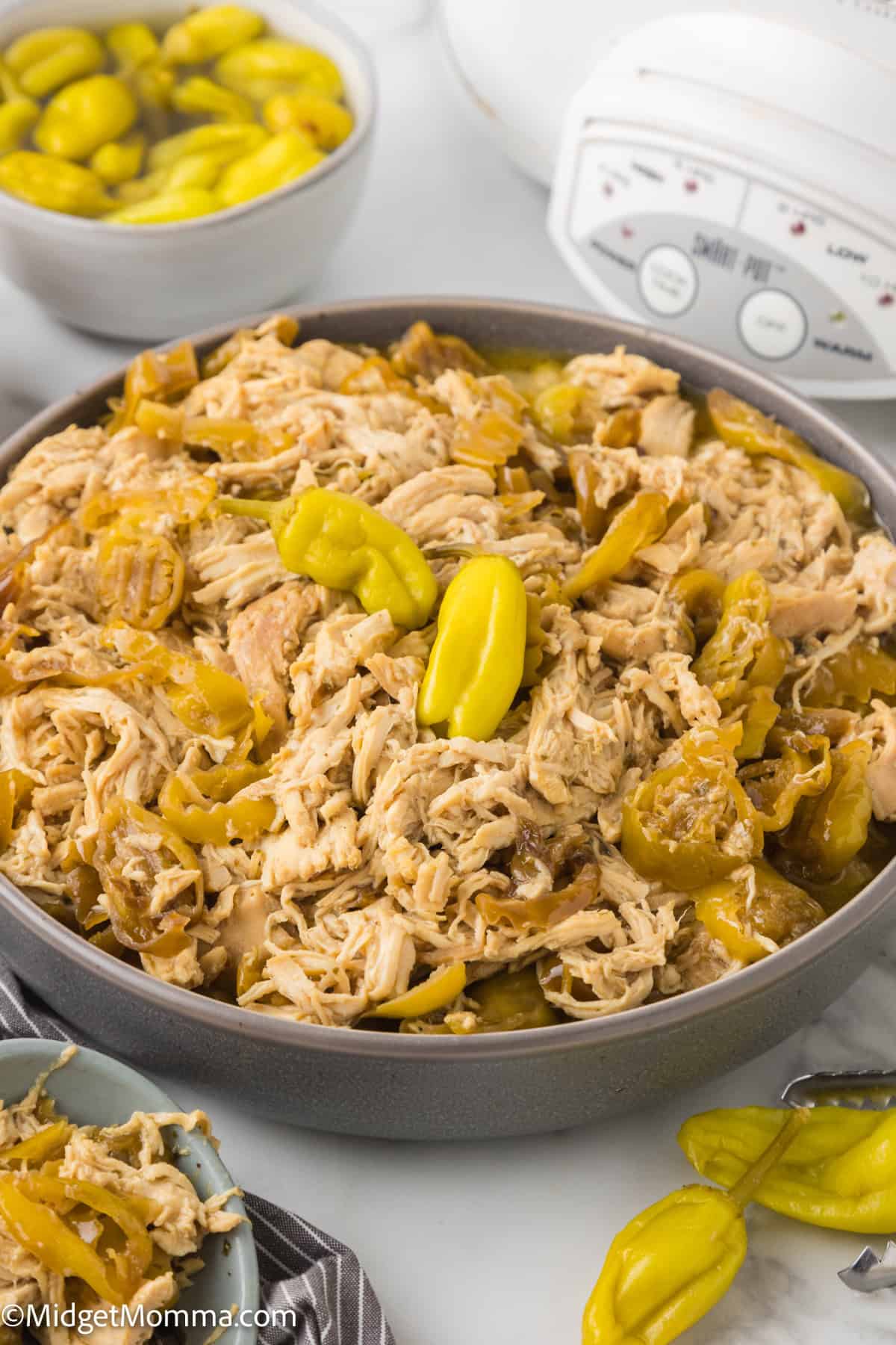 Bowl of slow cooker Mississippi Chicken with a slow cooker behind the bowl 