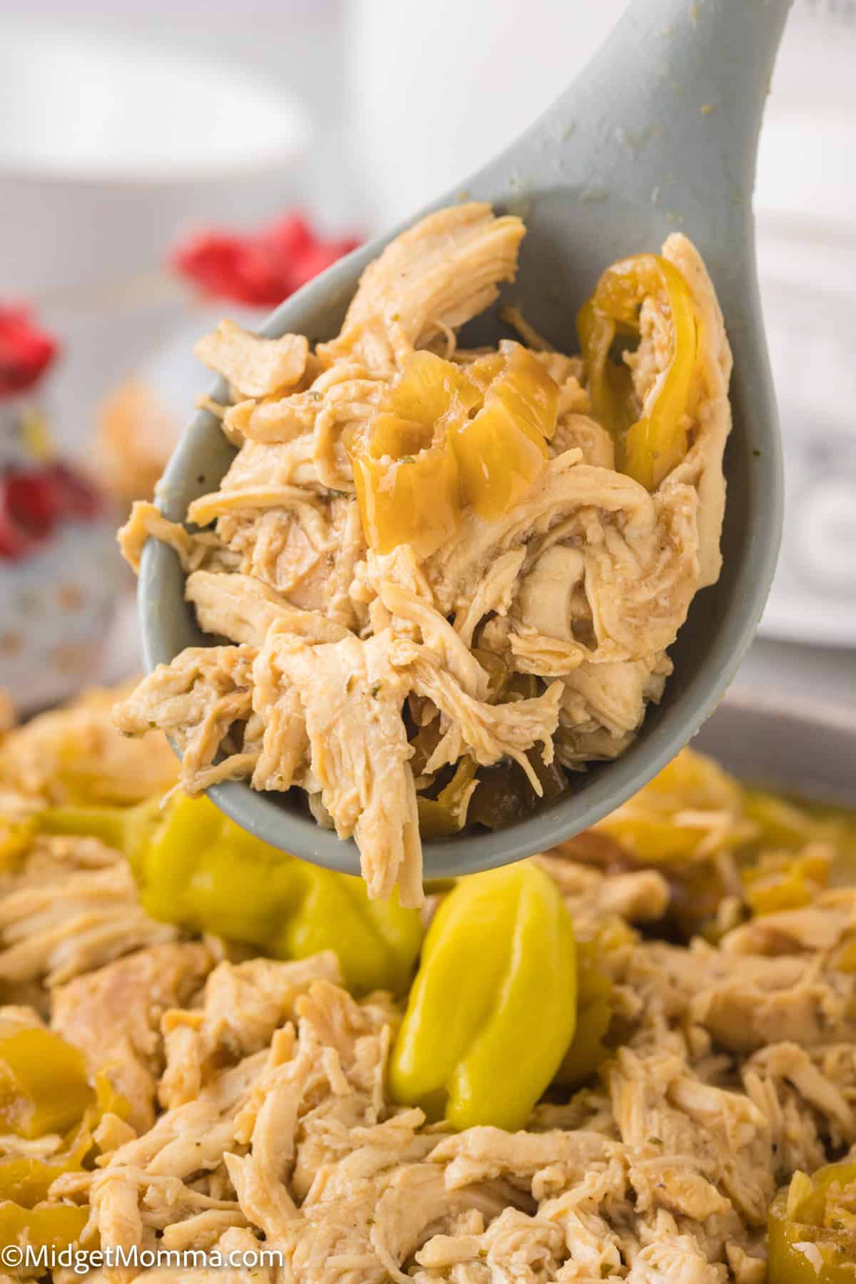 Shredded Mississippi chicken and sliced pepperoncini peppers are held above in a ladle over a dish of cooked mississippi chicken