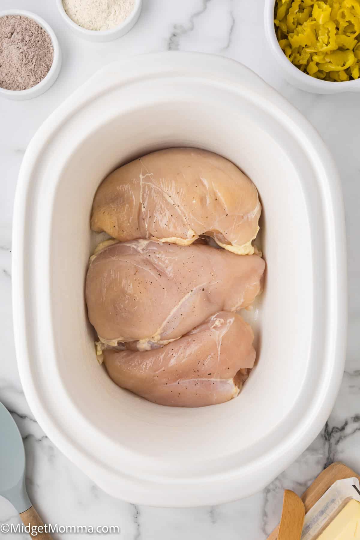 Raw chicken breasts in a white slow cooker