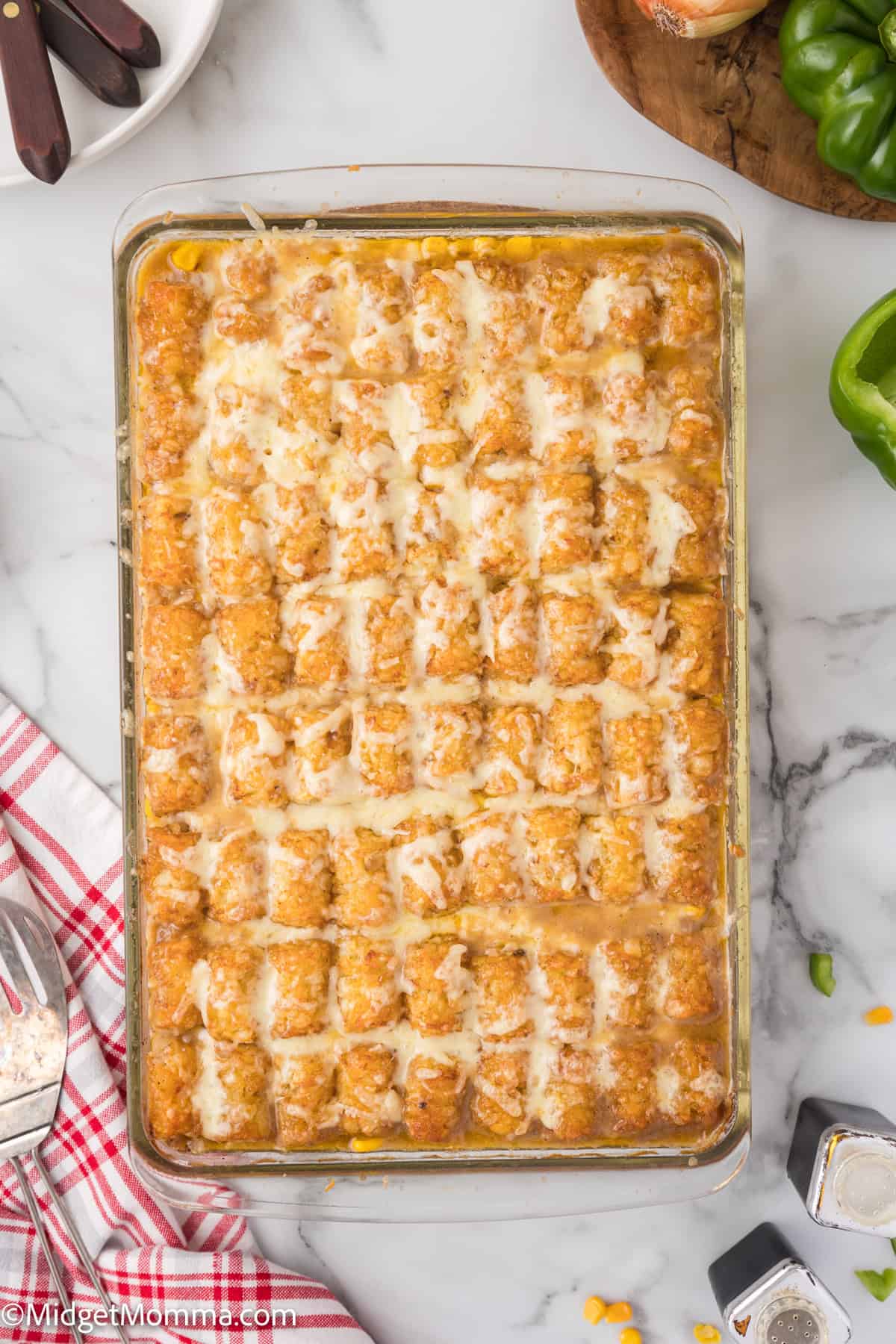 A rectangular casserole dish filled with neatly arranged rows of tater tots on top of a baked mixture, likely a tater tot casserole.