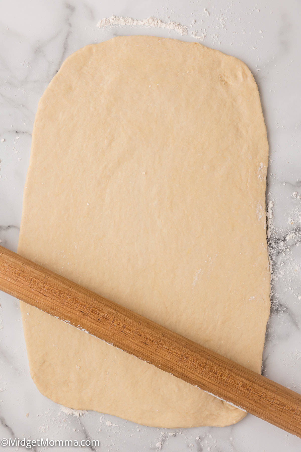 cinnamon roll dough being rolled out with a rolling pin