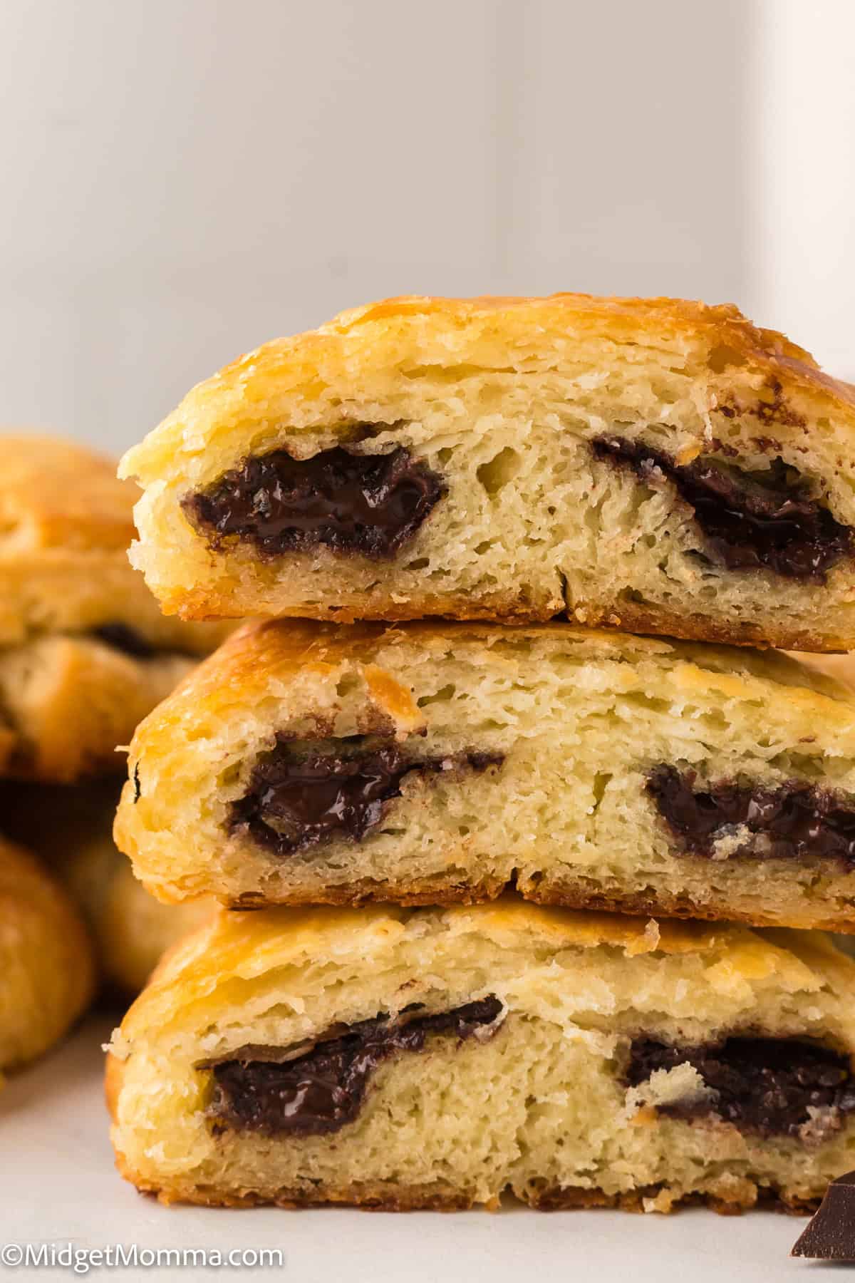 Three stacked pieces of chocolate-filled pastry, showing a flaky golden-brown crust and melted chocolate inside.