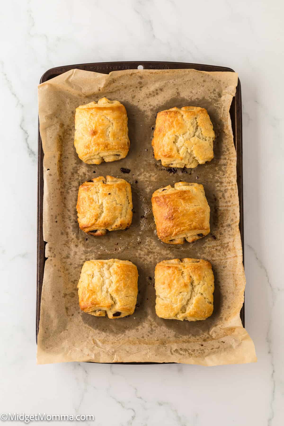 fresh baked homemade chocolate croissants on a baking sheet right out of the oven.