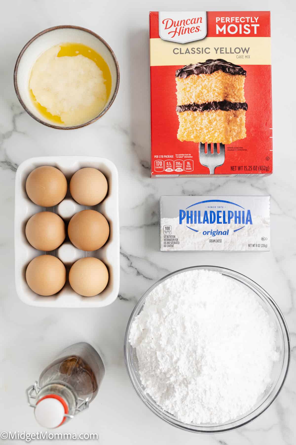 Gooey Butter Cake Ingredients. Ingredients laid out on a marble surface: boxed cake mix, block of cream cheese, eggs in a carton, a bowl of powdered sugar, melted butter, and a bottle of vanilla extract.